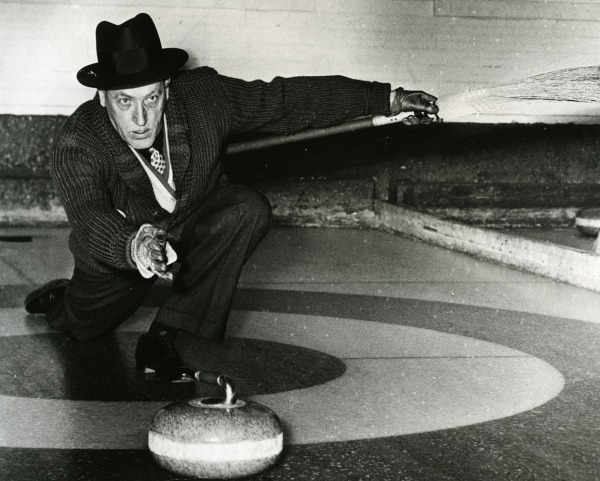 Photograph of Ken Watson holding curling broom out