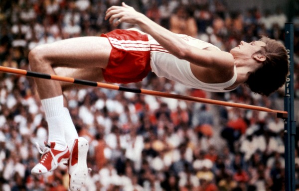 photograph of Greg Joy bending over high jump bar