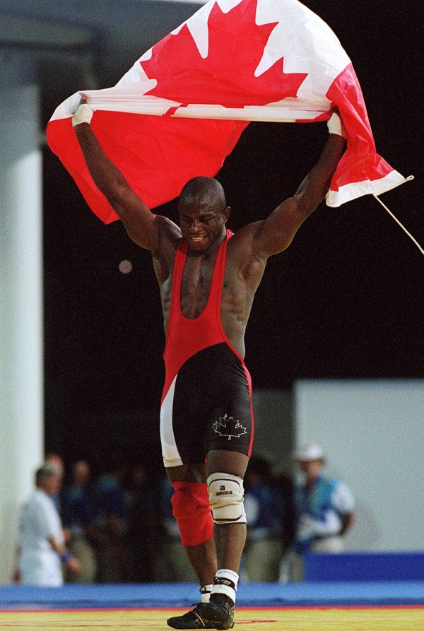 photograph of Daniel Igali holding Canadian flag over his head