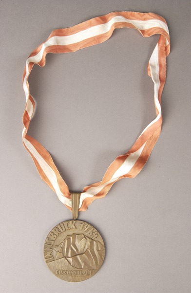bronze Olympic medal on red and white ribbon)
